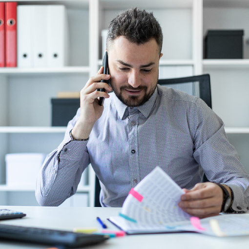 man talking on phone looking at papers