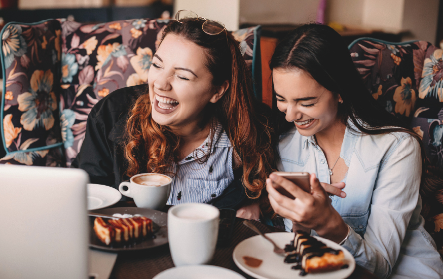 two women laughing at a café