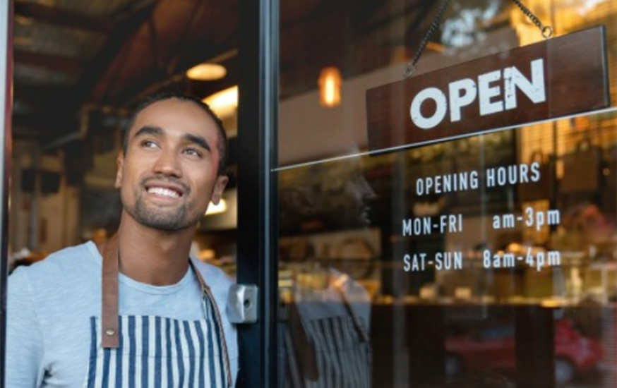 store owner looking out an open door and smiling